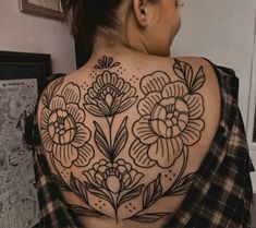 a woman's back tattoo with flowers on it