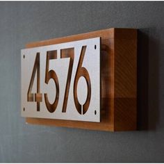 a house number sign mounted to the side of a wall with wood and metal numbers