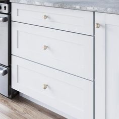 a kitchen with marble counter tops and white cabinets, gold pulls on the drawers in front of the stove