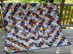 a colorful quilt is sitting on a wooden deck