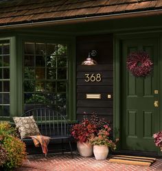 a green front door with two planters and a bench on the porch next to it