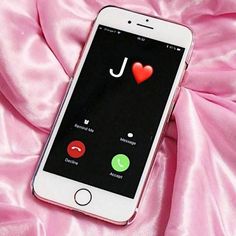 a cell phone with the letter k on it sitting on a pink satin material background