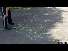 someone is writing on the pavement with grass in front of them and another person standing next to it