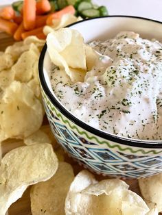 a bowl filled with dip surrounded by chips and veggies