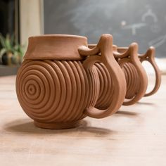 three clay mugs sitting next to each other on a table