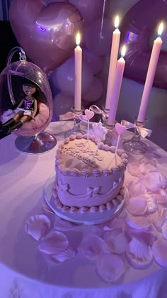 a birthday cake sitting on top of a table with lit candles in the middle and seashells around it