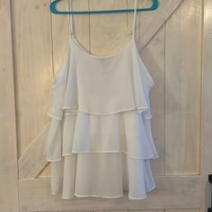 a white top hanging on a wooden wall next to a blue hanger with clothes