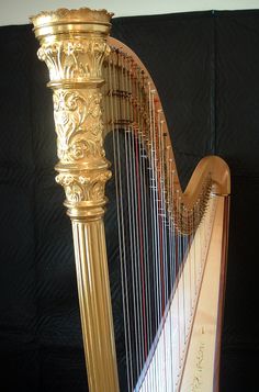 a gold colored harp is on display against a black background with white trimmings