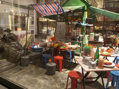 an assortment of food is displayed in a store window with chairs, tables and umbrellas