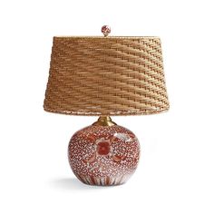 a red and white lamp sitting on top of a table next to a wicker shade