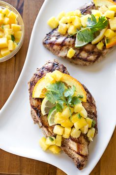 grilled pork chops with pineapple salsa and lime garnish on a white plate