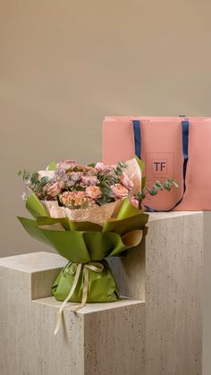 a bouquet of flowers sitting on top of a cement block next to a pink bag