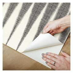 a woman is holding a piece of paper on top of a table next to a rug