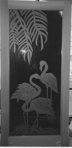 a black and white photo of two flamingos in front of a window with palm leaves