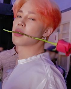 a young man with pink hair is holding a toothbrush in his mouth