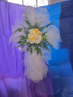 a vase filled with yellow flowers on top of a blue table cloth covered chair next to a purple curtain