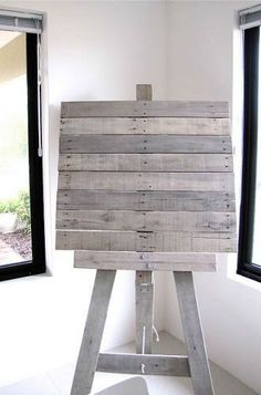 a wooden easel sitting in front of two windows