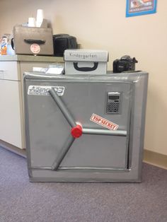 an office cubicle with a large metal box on the floor next to it's door