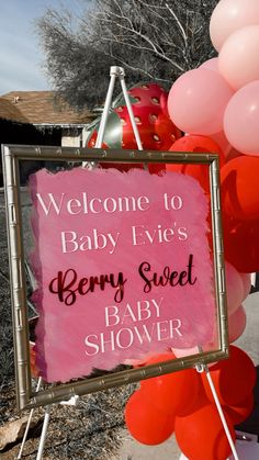 a baby shower sign with balloons in the background