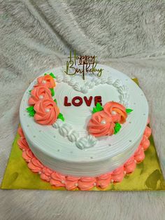 a heart shaped cake with flowers on it sitting on a yellow and white tablecloth