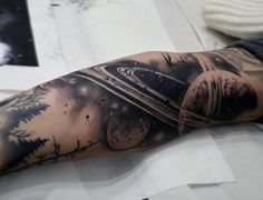 a man with a black and white tattoo on his arm that has an image of the planets