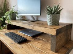 a wooden desk with a computer and keyboard on it next to a potted plant