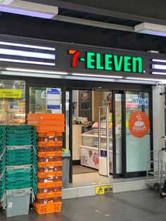 the 7 eleven store front is lit up with neon signs and orange boxes stacked outside