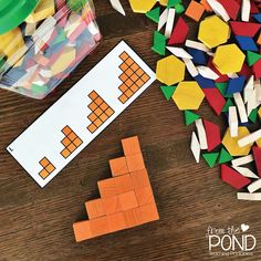 a pile of wooden blocks next to a plastic container filled with colored pegs on top of a table