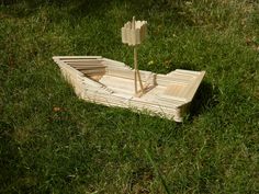 a small boat made out of wooden planks in the grass with a plant sticking out of it