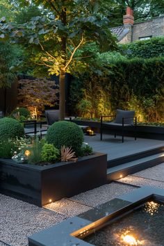 an outdoor garden is lit up at night with lights on the ground and trees in the background