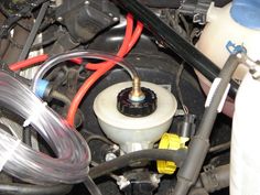 the engine compartment of a car with hoses connected to it and an oil can