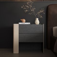 a nightstand with a vase on it next to a bed