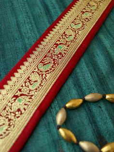 A gorgeous trim created with Banarasi brocade weave, with peacocks, parrots and elephants woven in gold on to a maroon silk fabric. The trim has a beautiful soft hand feel, and very light drape. The result - a trim that will convert your every project into a designer creation! Price for 1 mtr Size - 5 cm W Use it to embellish your denim jackets, or border your sarees. Or create home décor like lamps or curtain ties. Or accessories like hair bands. One trim, countless possibilities. We have many Banarasi Border Lace, Traditional Brocade Wear With Zari Work For Puja, Red Traditional Wear With Embroidered Border, Red Brocade Choli With Cutdana, Red Traditional Art Silk Wear, Diwali Red Choli With Traditional Patterns, Red Choli With Traditional Patterns For Diwali, Red Traditional Wear With Zari Weaving, Traditional Red Choli With Cutdana