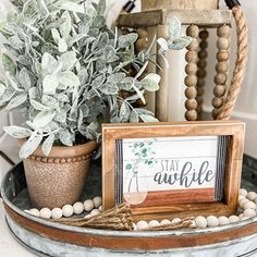 a potted plant sitting on top of a table next to a sign that says stay awhile