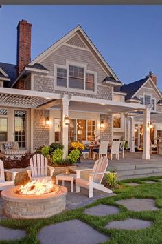 an outdoor fire pit in front of a house with lawn chairs and patio furniture around it