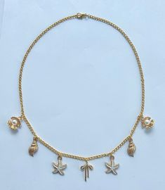 The Coastal Bow Charm Necklace is the perfect addition to any outfit, effortlessly elevating your style with its charming and beautiful design. The delicate bow charm at the center, surrounded by the cute white starfish, the gold conch shells, and the clam shells with their gorgeous pearls, creates a stunning piece that complements any summer look.  Pair this necklace with a breezy sundress for a day out, or add it to a t-shirt over your swimsuit for a casual look. The necklace also looks great with a simple tank top and denim shorts, sprucing up your everyday attire. Ideal for summer and beach outings, the Coastal Bow Charm Necklace captures the essence of the seaside with its nautical-inspired charms. Perfect for a beach party or a seaside brunch! The necklace is 18 inches long and handm Charm Jewelry For Beach, Gold Starfish Charm Necklace For Beach Season, Beach Jewelry With Charms In Ocean-inspired Style, Gold Necklace With Starfish Charm For Beach Season, Gold Charms Jewelry For Vacation, Gold Vacation Jewelry With Charms, Vacation Gold Jewelry With Charms, Ocean-inspired Jewelry With Charms For Beach, Ocean-inspired Beach Jewelry With Charms