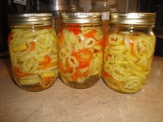 three mason jars filled with pickled onions and peppers