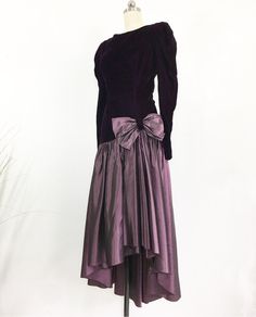 The perfect winter party dress! Long sleeve velvet deep purple bodice with a layered purple taffeta full skirt, adorned with a bow. The drop waist gives this dress a flapper feel. Asymetrical hemline, unlined, hidden zipper in the back. Deep V-back neckline. Gorgeous and ready for a fun night. DETAILS: Label: None Fabric: Velvet, Taffeta Lining: None Decade: 1980's MEASUREMENTS: Shoulders: 15'' Bust: 32'' Waist: 26'' Length: 48''front, 54''back Hips: 32'' Sleeves: 26'' Sleeve opening: 6'' widest Purple Velvet Dress For Party, Purple Velvet Party Dress, Formal Purple Velvet Dress, Elegant Purple Velvet Dress, Purple Formal Dress For Fall, Fall Wedding Purple Dress, High Low Cocktail Dress, Columbia Tn, Country Dresses