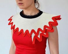 a woman in a red dress with white and black trims on her neckline