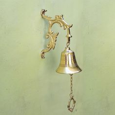 a golden bell hanging from the side of a green wall