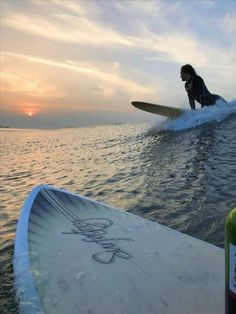 a person riding a surfboard on top of a body of water in the sunset