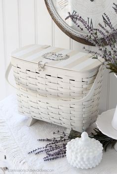 a white basket sitting on top of a table next to a vase filled with flowers