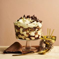 there is a dessert in the glass bowl on the table next to gold spoons