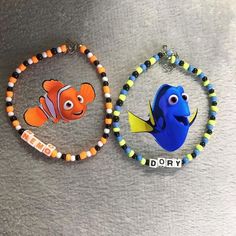 two bracelets with finding nemo and dory charms attached to them on a gray surface