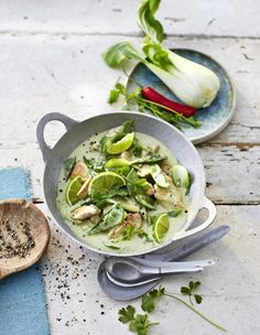 a bowl filled with green vegetables next to spoons