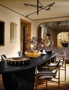 a dining room with black table cloths and gold vases on the centerpiece