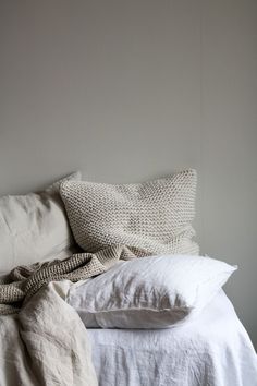 an unmade bed with white sheets and pillows