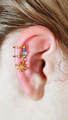 Express your unique style with the Celestial Whisper Ear Cuff, featuring ethically sourced gemstones and a celestial charm. Lightweight and versatile, this cuff can be worn on your rook, anti-tragus, tragus, or helix, adding a touch of celestial elegance to any look. No piercing needed—just adjust for a perfect fit! Personalize Your Ear Cuff: Choose Your Top Gemstone: Select from a range of natural stones, each with unique properties and meanings. Choose Your Bottom Gemstone: Pair it with anothe