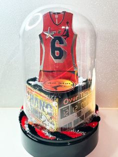 a basketball jersey under a glass dome on top of a table next to other items