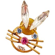 a gold brooch with pink, blue and white stones